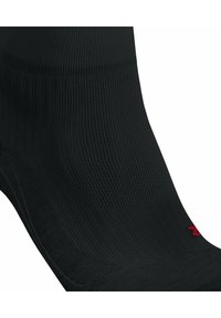 Calcetín negro con un diseño de punto texturizado. Presenta una puntera y un talón reforzados, con un pequeño logotipo rojo cerca de la parte superior.