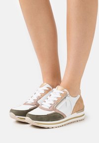 Baskets légères avec un mélange de cuir blanc, de suède taupe et vert, agrémentées d'un accent doré et d'un détail de fermeture éclair sur le côté.