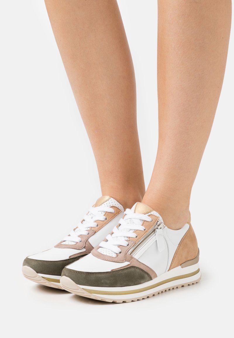 Baskets légères avec un mélange de cuir blanc, de suède taupe et vert, agrémentées d'un accent doré et d'un détail de fermeture éclair sur le côté.