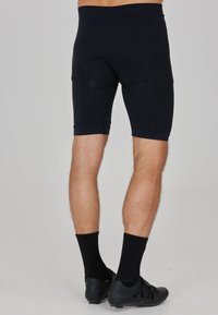 Zwarte compressie-short met een aansluitend ontwerp, die tot halverwege de dij reikt. Gemaakt van een gladde stof met een strakke tailleband en minimale naden.