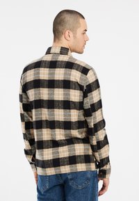 Heren overhemden in beige, zwart en grijs. Gemaakt van textuurstof met een kraag met knopen en lange mouwen, voorzien van een ruitpatroon.