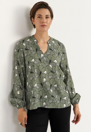 Løstsiddende grøn bluse med sort-hvidt blomsterprint, V-hals og lange ærmer med elastiske manchetter. Letvægts tekstureret stof.
