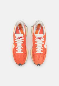 Orangene Wildledersneaker mit weißen Schnürsenkeln, schwarzer Gummisohle und einem Retro-Design. Verfügt über ein dezentes Logo und strukturierte Materialien.