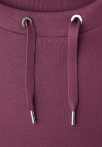 Gros plan sur le tissu d'un sweat à capuche couleur bordeaux avec deux cordons assortis passant à travers des œillets métalliques et des embouts métalliques aux extrémités.