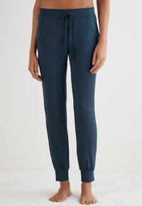 Dunkelblaugrüne Jogginghose aus weichem Stoff, mit einem elastischen Bund und Kordelzug, Seitentaschen und schmal zulaufenden Bündchen.