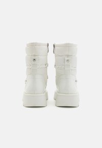 Vita puffer snöboots med en tjock, texturerad ovansida och slät sula. Har en dragkedja och knapppynt på baksidan. Klumpig plattformdesign.