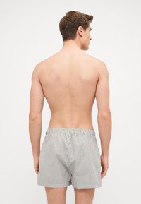 Boxers en coton rayés avec une taille élastique, présentant de fines lignes verticales en blanc et marine. Design simple sans détails supplémentaires.