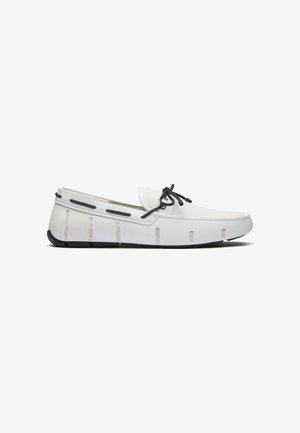 Witte leren loafer met zwarte veters en zwarte zool, met zijventilatieroosters en een gestikt moc toe-ontwerp.