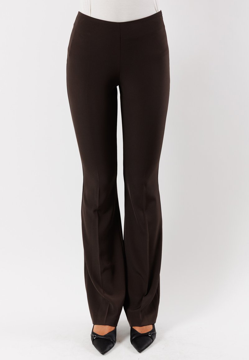 Pantaloni marroni svasati in tessuto liscio con vita alta e tasche laterali, abbinati a scarpe nere a punta.