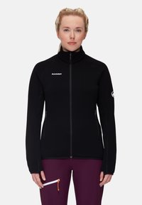 Giacca in pile nera con colletto alto, zip completa e polsini elasticizzati. Presenta un logo bianco sul petto e due tasche laterali con zip.