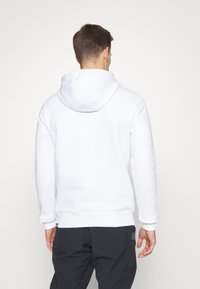 Sudadera blanca con capucha ajustable, puños y dobladillo acanalados. Material suave; presenta un corte holgado y no tiene gráficos ni patrones visibles.