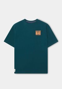 Camiseta de algodón color verde azulado oscuro con mangas cortas, con un gráfico naranja "SUEÑA EN GRANDE" en el pecho y una pequeña etiqueta en el dobladillo.
