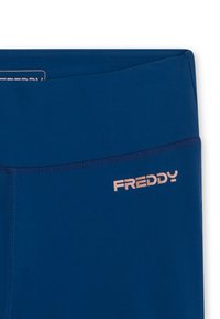 Prima di un paio di leggings sportivi blu con vita alta e il logo "FREDDY" in rosa chiaro sulla parte destra dell'anca.