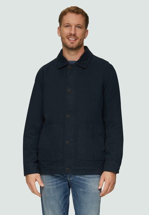 Marineblauwe button-up jas met een staande kraag, twee voorzakken en een gestructureerde stof. Draag deze over een grijze trui en jeans.
