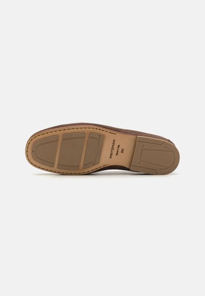 Semelle de chaussure en daim marron avec une surface texturée, présentant un motif de grip en caoutchouc et un détail de couture le long du bord. Inclut un logo.