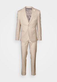 Costum bej, croit dintr-un material ușor. Dispune de un sacou cu un singur nasture, rever cu tăietură în formă de v și pantaloni cu front neted, cu o textură fină.