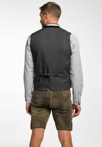 Graues Nadelstreifen-Weste mit abgerundetem Saum, verstellbarem Rückengurt, kombiniert mit olivgrünen Shorts mit seitlichen Taschen.