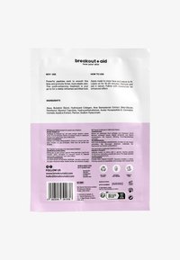 Rückseite der Verpackung einer Hautpflege-Maske in Weiß und Lila. Der Text enthält Anweisungen zur Anwendung, Inhaltsstoffe und einen Barcode.