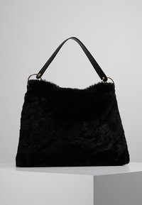 Czarna torebka z futra syntetycznego o miękkiej teksturze, z wyraźnie zdefiniowanym kształtem, czarnym skórzanym paskiem i złotymi akcentami sprzętowymi.