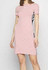 Różowa sukienka Fila z krótkimi rękawami, z bocznymi paskami w czerni i bieli, wykonana z miękkiego materiału i dopasowanego kroju.