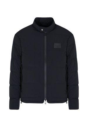Giacca nera imbottita da uomo con colletto alla coreana, cerniera frontale, tasche laterali e una piccola toppa rettangolare sul petto.