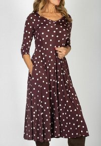 Brązowa sukienka w kropki z rękawami do trzech czwartych, rozszerzanym fasonem, okrągłym dekoltem i kieszeniami. Wykonana z miękkiej tkaniny o gładkiej fakturze.