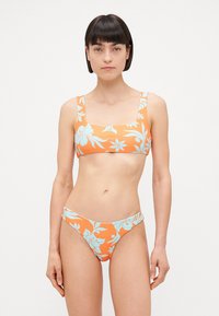 Orangemönstrad bikiniuppsättning med fyrkantig halsringning och låg midja, prydd med blå blommönster. Mjuk, slät tygtextur.