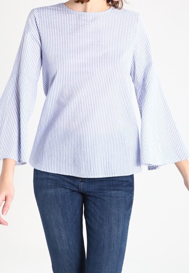 Top a righe blu chiaro e bianche, a maniche lunghe con scollatura rotonda e maniche a campana; aderente sul busto e morbido sotto.