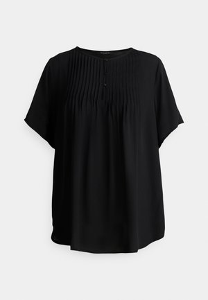 Blouse noire à manches courtes en tissu léger, avec des plis à l'avant, un col rond et trois boutons noirs pour la fermeture.