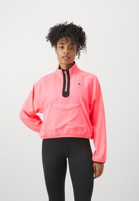 Veste pull rose avec un col zippé à mi-hauteur, détail de zip noir et poche avant ; taille et poignets élastiques, fabriquée en tissu lisse.