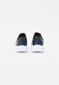 Chaussures de sport avec une tige noire et des accents en maille bleue, des détails verts contrastants, et une semelle blanche avec un motif texturé.
