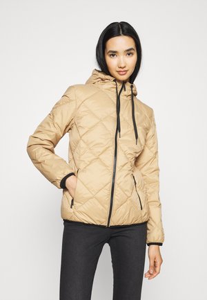 Beige pufferjakke med hætte, der har et diamantquiltet mønster, sort lynlås og justerbare snore. Sorte manchetter og lommer medfølger.