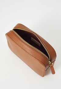 Piccola pochette rettangolare in pelle marrone con superficie texturizzata e zip dorata parzialmente aperta su sfondo bianco.
