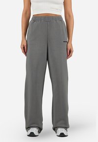 Gray wide-leg sweatpants with an elastic waistband and side pockets, featuring a small black logo on the left leg. Soft fabric texture.