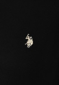 Black cotton fabric with a small white embroidered logo featuring a horse and rider, positioned on the left side.