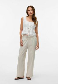 Witte linnen top met kantafwerking en knoopsluiting, gecombineerd met lichtbeige wijde broek, met een relaxte pasvorm en een trekkoord in de taille.