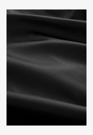 Sort stof med en glat, let skinnende overflade, der viser subtile folder og rynker, hvilket skaber dybde og fluiditet i designet.