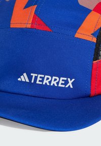 Kék sapka piros és narancssárga részletekkel, sima anyagból készült. Az elülső panelen fehér színnel a "TERREX" logó található.