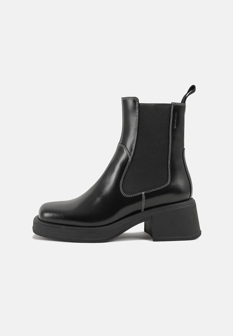Botte Chelsea noire avec panneau latéral élastique, languette à l'arrière, talon épais et semelle épaisse, vue de côté sur un fond uni clair.