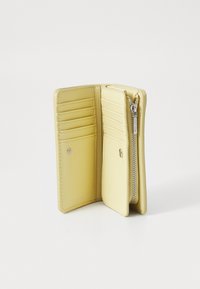 Portefeuille en cuir jaune avec six emplacements pour cartes, une section zippée et une fermeture à bouton-pression. Texture lisse et design minimaliste.