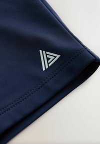 Tmavě modrá látka s bílým geometrickým trojúhelníkovým logem tvořeným třemi paralelními liniemi a stylizovanou "7" u šitého okraje.