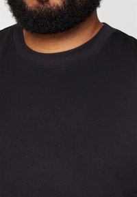 Schwarzes T-Shirt mit kurzen Ärmeln aus glattem Baumwollstoff, mit rundem Ausschnitt. Keine sichtbaren Logos oder Muster. Einfaches Design.
