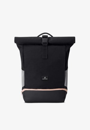 Fekete roll-top hátizsák elülső csattal, szürke oldalpanelek, bézs cipzáras alsó rekesz és kis téglalap alakú logófolt.