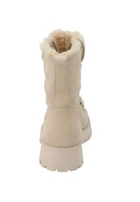 Beżowe botki za kostkę z gładkiej skóry, z futrzanym wykończeniem, teksturowaną podeszwą i dekoracyjnymi sznurowadłami. Zaokrąglony czubek i wysokość do kostki.