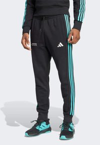 Black sweatpants featuring turquoise stripes along the sides, elastic waistband, and white Adidas logo. Made from soft, breathable fabric.
