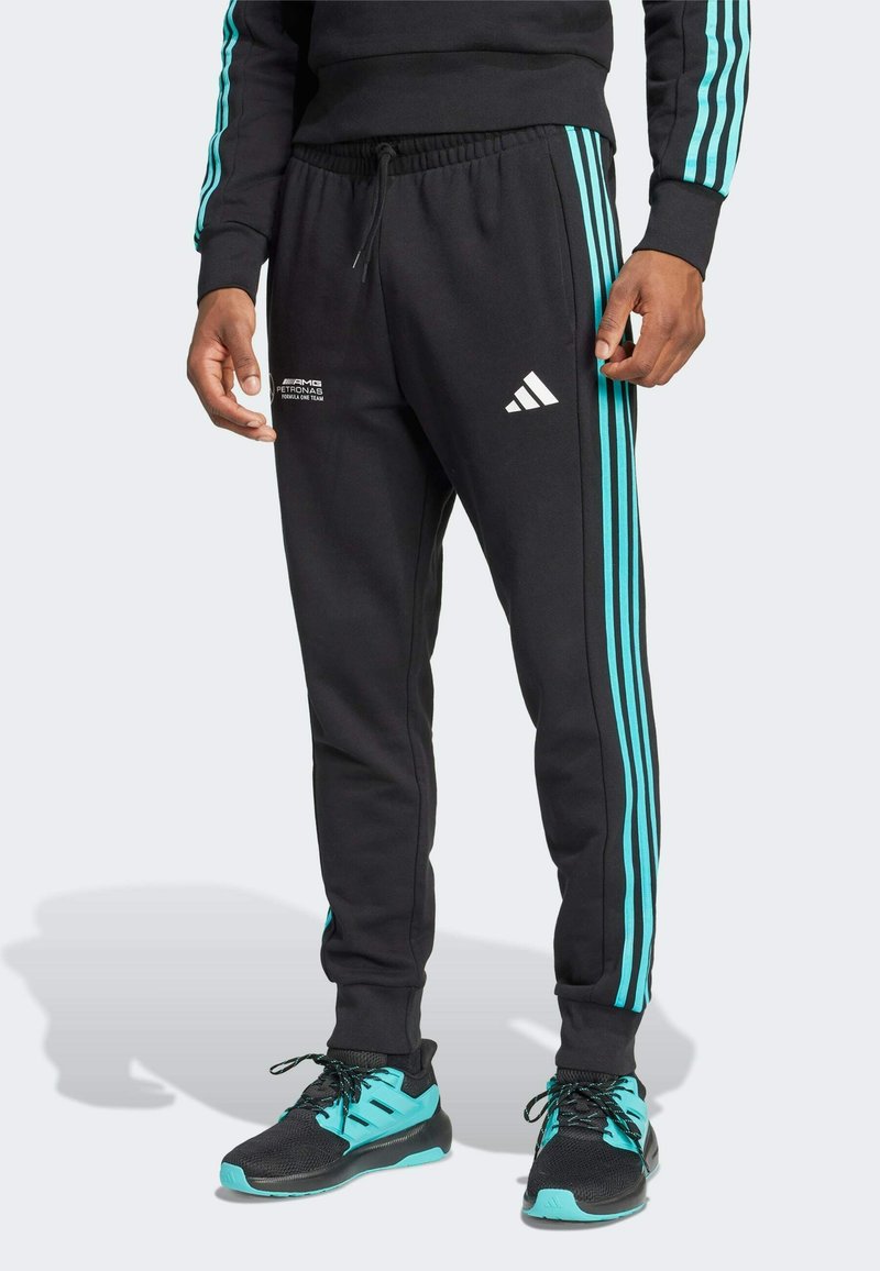 Black sweatpants featuring turquoise stripes along the sides, elastic waistband, and white Adidas logo. Made from soft, breathable fabric.