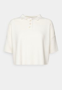Polo tričko s krátkým rukávem a zkrácenou délkou v měkké krémové látce. Obsahuje límec a čtyři neutrální knoflíky vpředu.