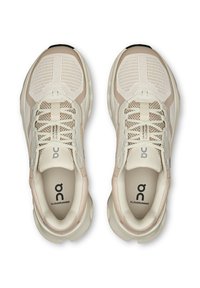 Beige és krém színű On Cloudrunner futócipő párja felülről nézve, hálós anyaggal és fűzős dizájnnal.