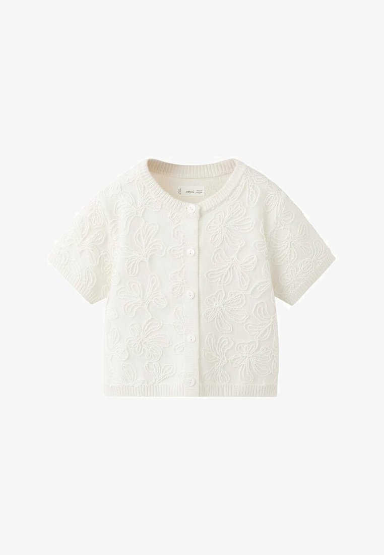 Cardigan à manches courtes de couleur crème en tissu texturé, orné de broderies florales et doté de cinq boutons sur le devant.
