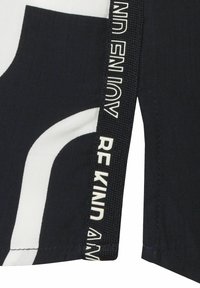 Marineblauwe stof met wit abstract patroon; heeft een geweven zwart label met de tekst "WEES VRIENDELIJK". Smooth textuur met scherpe randen.